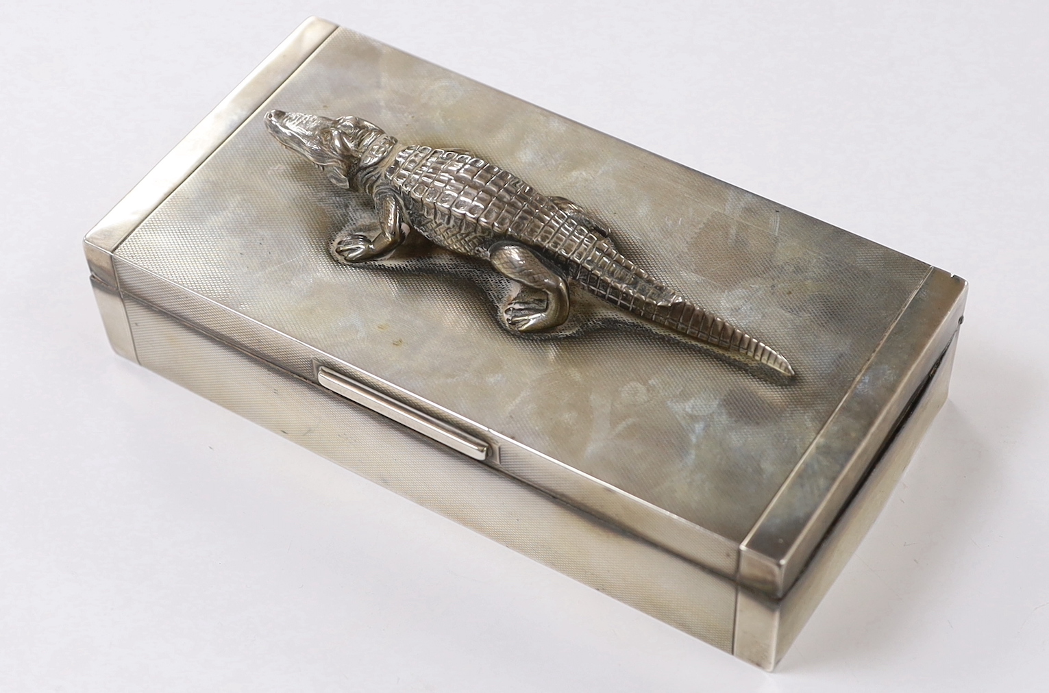 A George VI part engine tuned silver mounted rectangular cigarette box, with white metal crocodile surmount and interior presentation inscription relating to 'Lt. Colonel K.F.G. Stronach', maker Hamilton & Co, London, 19